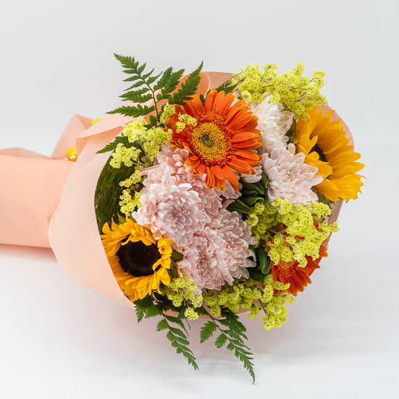 Bouquet of flowers wrapped in pink paper on a white background