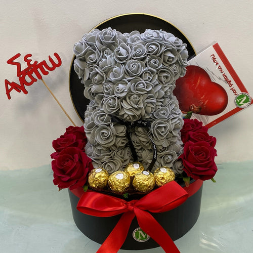 Teddy bear made of silver roses with red and gold accents in a box on a white background