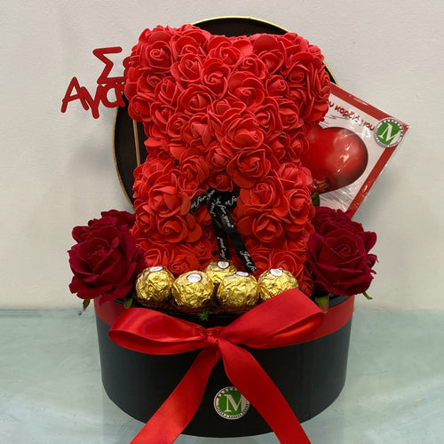 Teddy bear made of red roses in a black box with a red ribbon on a light gray background