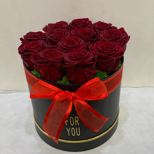 Heart-shaped box of red roses with a red bow on a white background