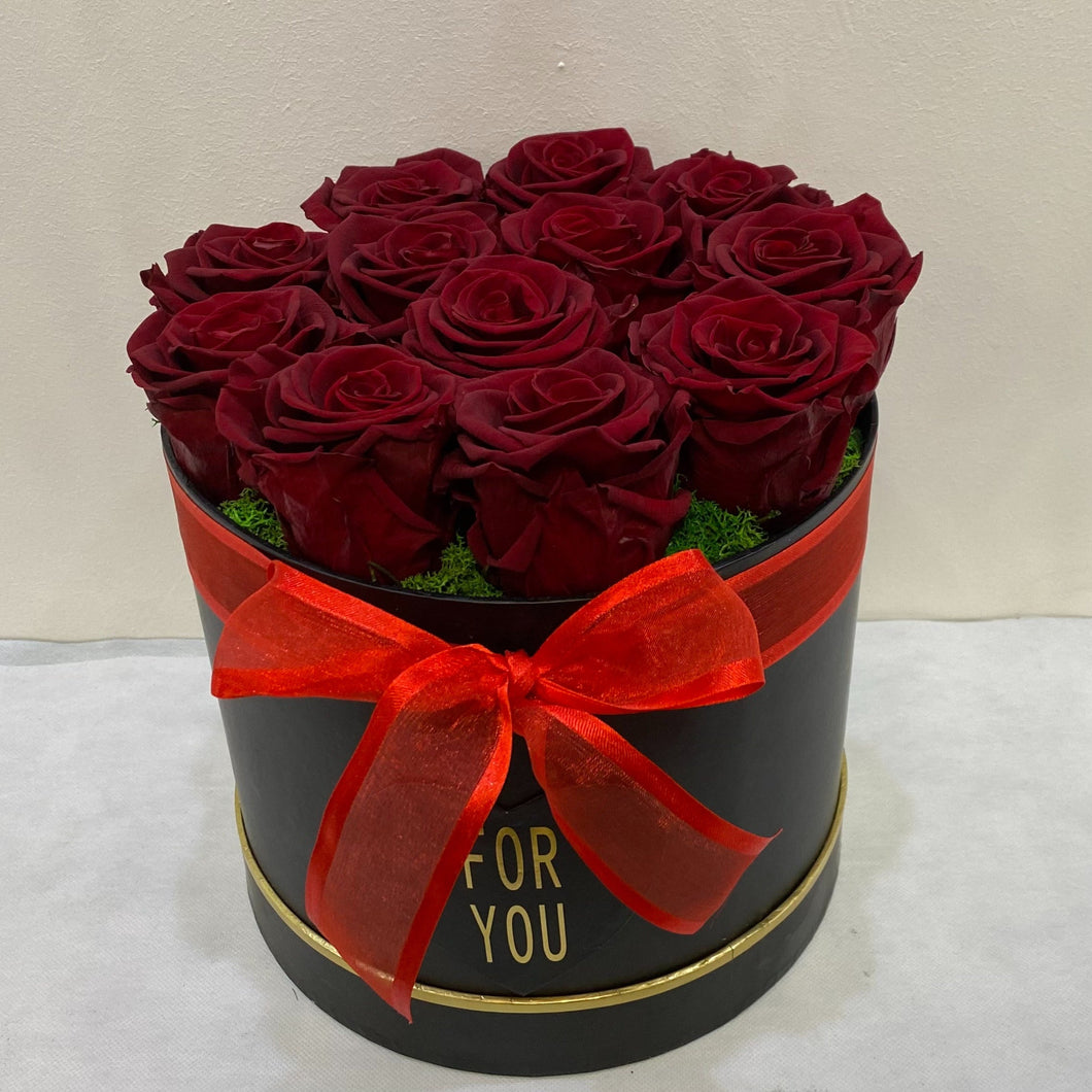 Heart-shaped box of red roses with a red bow on a white background