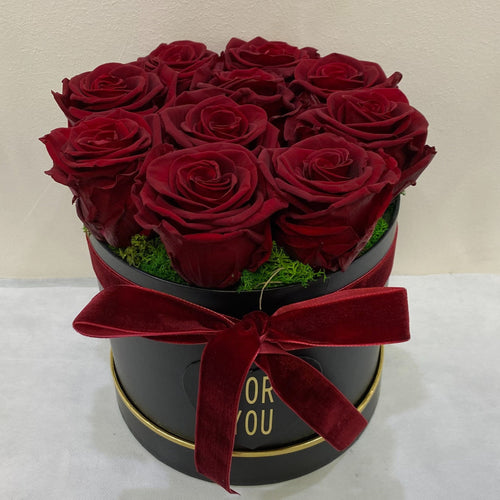 Black round box with red roses and a red bow on a white background