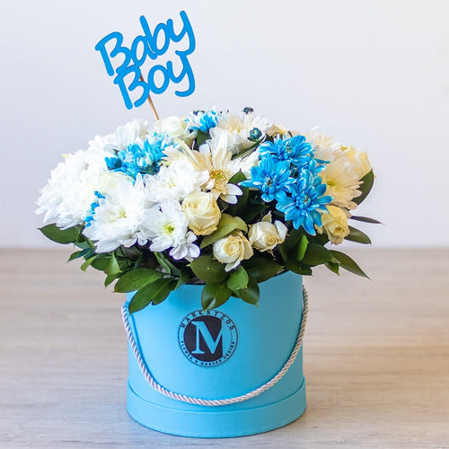 Floral arrangement in a blue box with 'Baby Boy' sign on a wooden surface