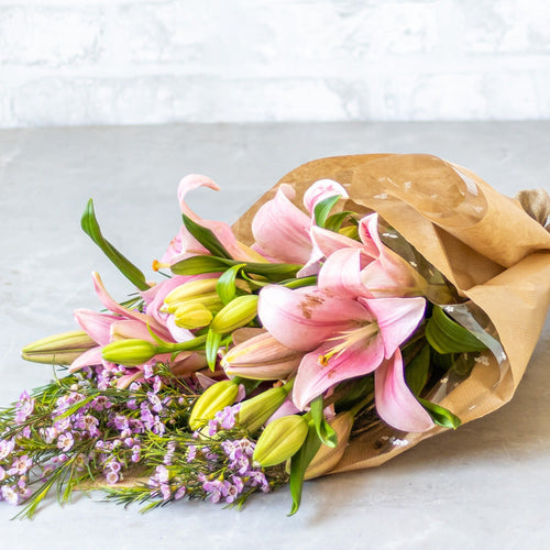 Bouquet of flowers wrapped in brown paper on a light gray surface