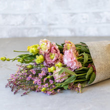 Load image into Gallery viewer, Bouquet of flowers wrapped in brown paper on a light surface with a white background
