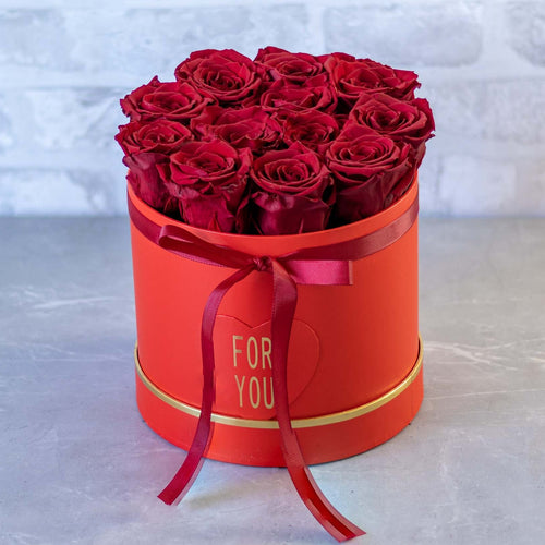 Red roses in a round red box with 'For You' ribbon on a light gray background