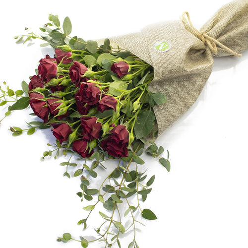Bouquet of red roses with greenery wrapped in burlap on a white background