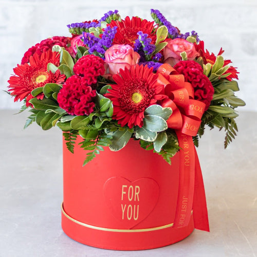 Colorful bouquet of flowers in a red box with 'For You' text on a light background