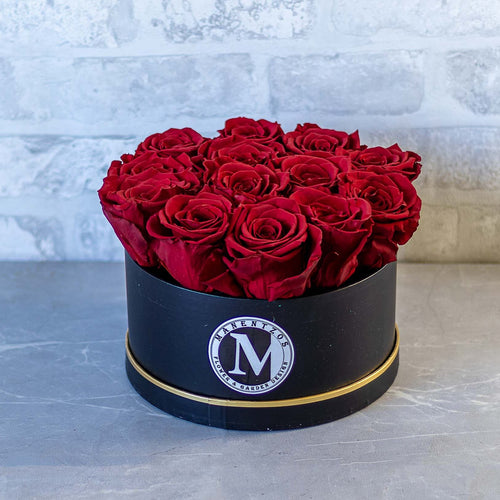 Black round box with red roses on a gray surface with a light gray textured background