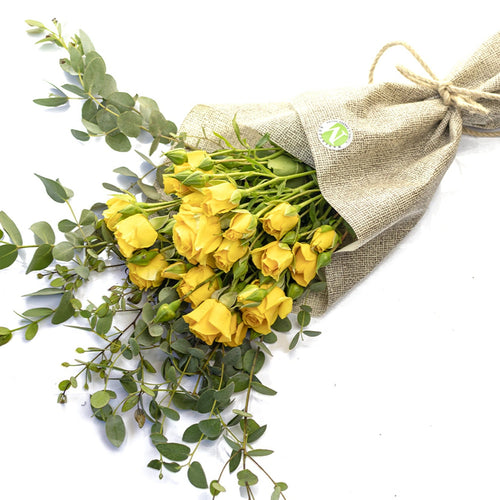 Bouquet of yellow flowers wrapped in burlap on a white background